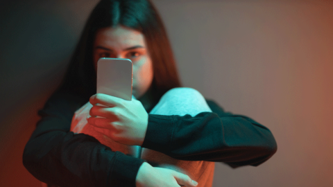 Teenage girl sat on floor, absorbed in mobile phone content