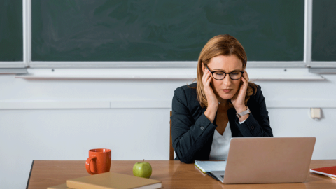 Female teacher looking overwhelmed at the her computer screen.