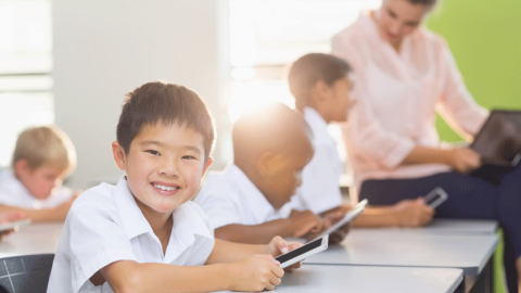 Primary school children using smartphones with the teacher's supervision.