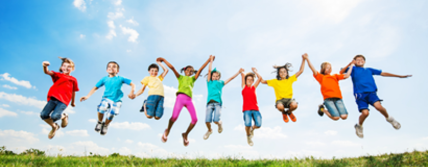 Mixed group of children in colourful clothing jumping on grass