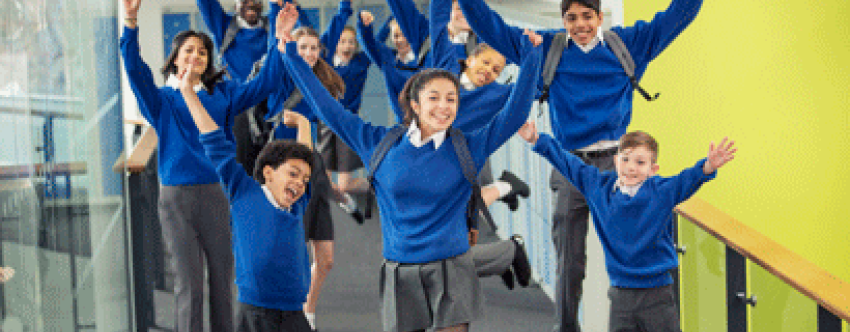 Mixed group of enthusiastic students in uniform jumping in school corridor